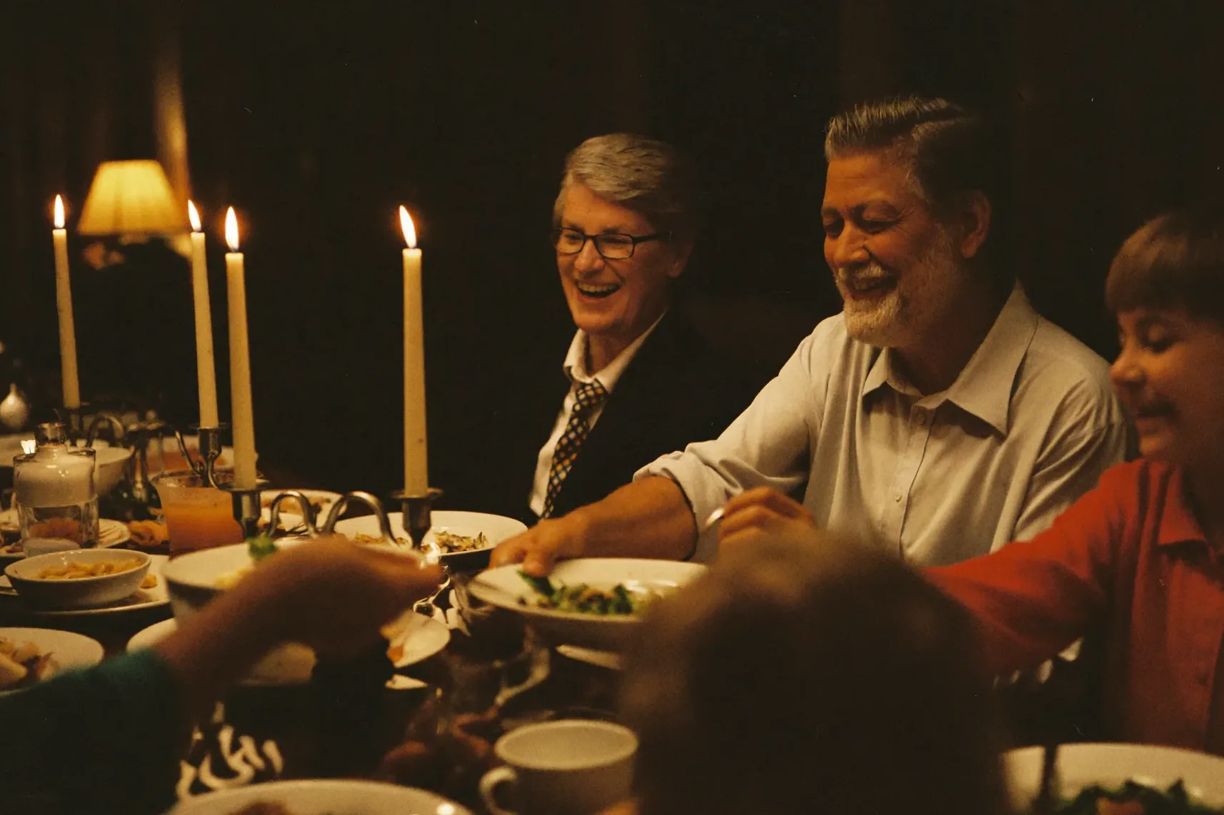 Three generations of a family passing dishes around a Sunday dinner table